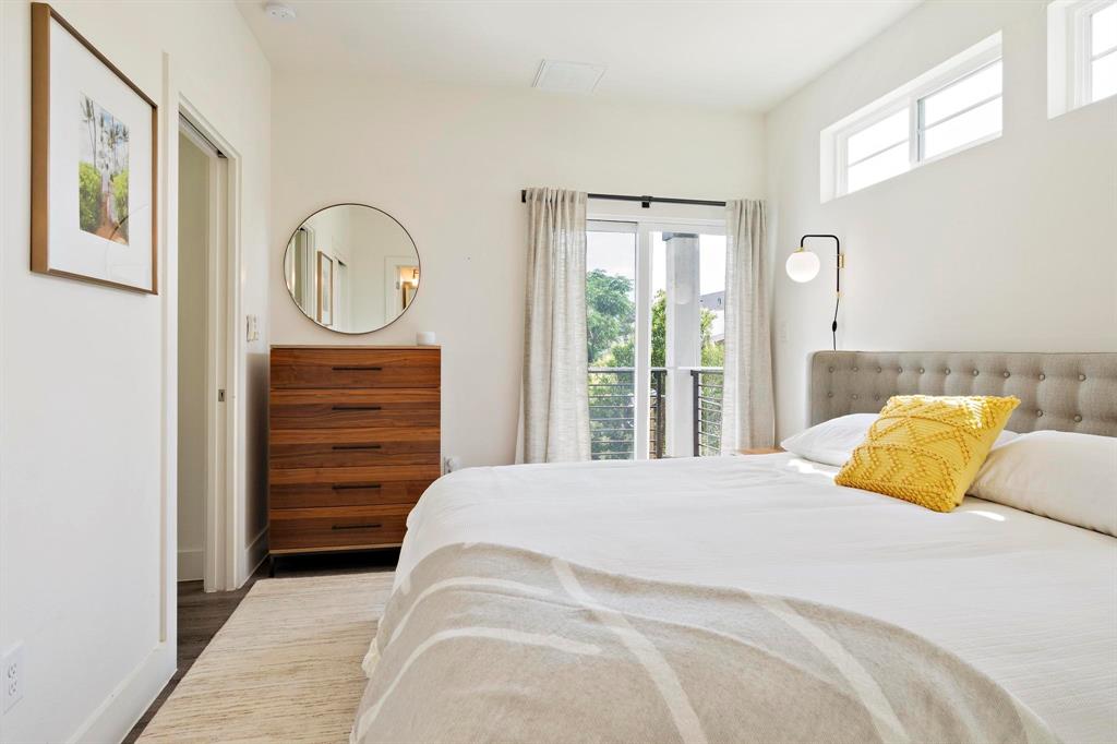 911 Stobaugh Street, Unit 2 Austin, TX 78757 - Photo 16 of 26 Bedroom featuring a private balcony access, high transom windows, a tufted headboard, and rich wood-finish flooring