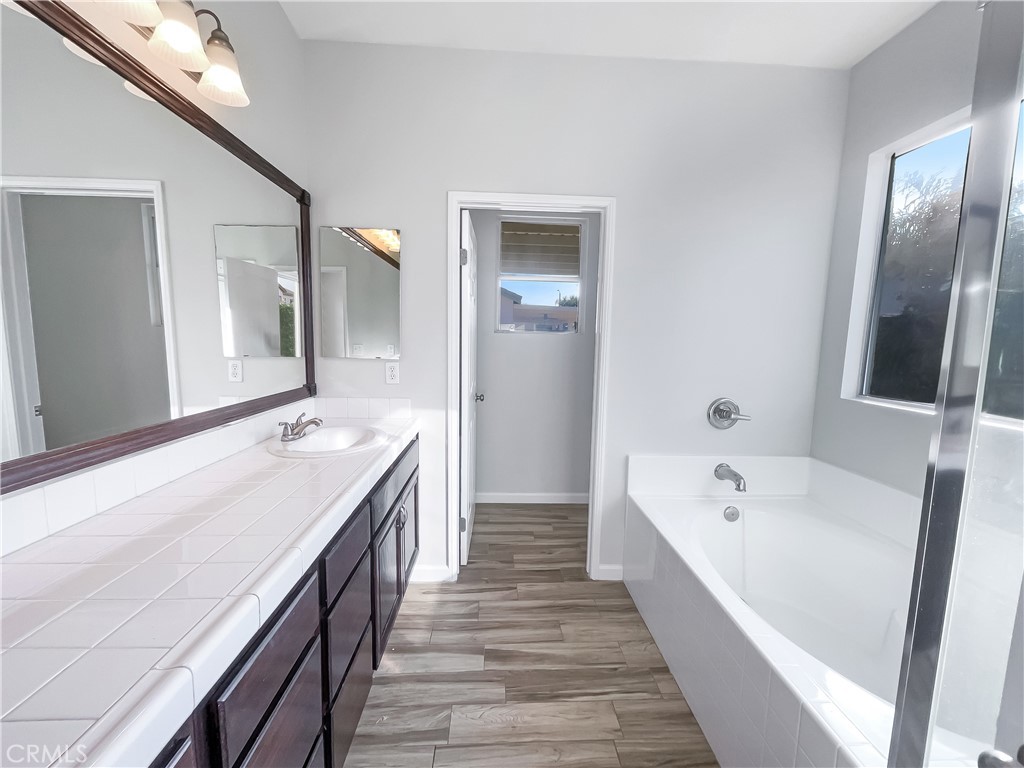 3429 Catalina Avenue Hemet, CA 92545 - Photo 16 of 20 a spacious bathroom with a bathtub double vanity sink and a large mirror