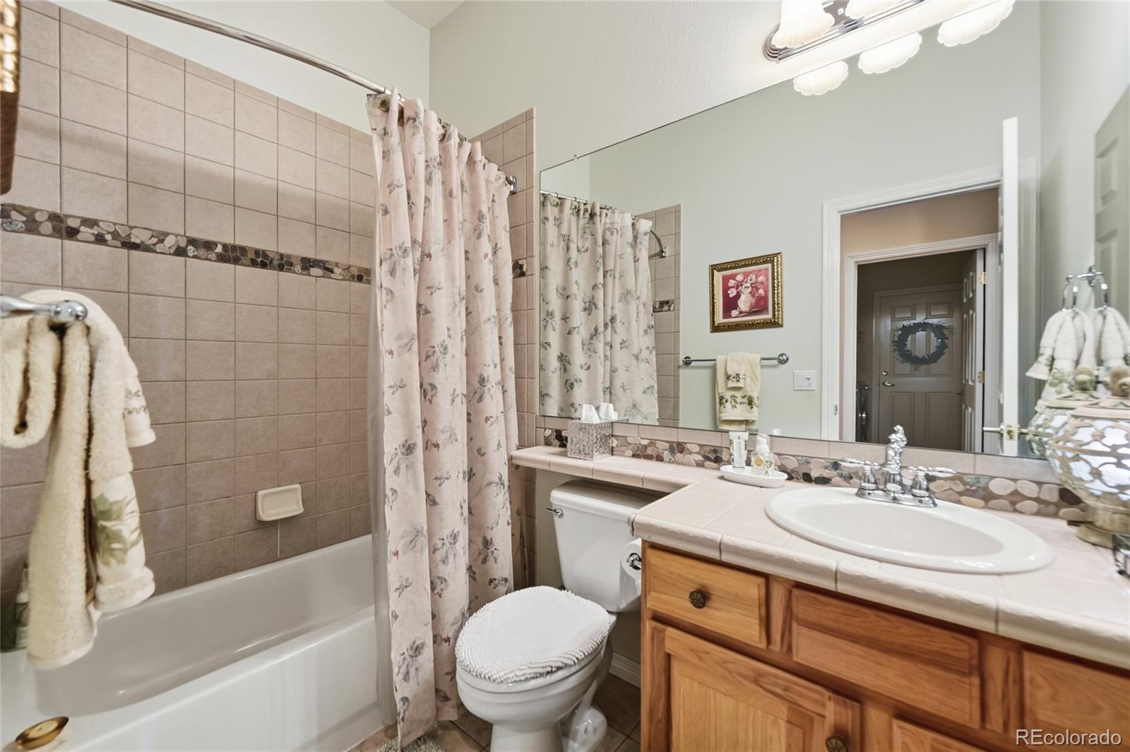 2626 Pemberly Avenue Highlands Ranch, CO 80126 - Photo 16 of 49 a bathroom with a sink a toilet a mirror a bathtub and shower