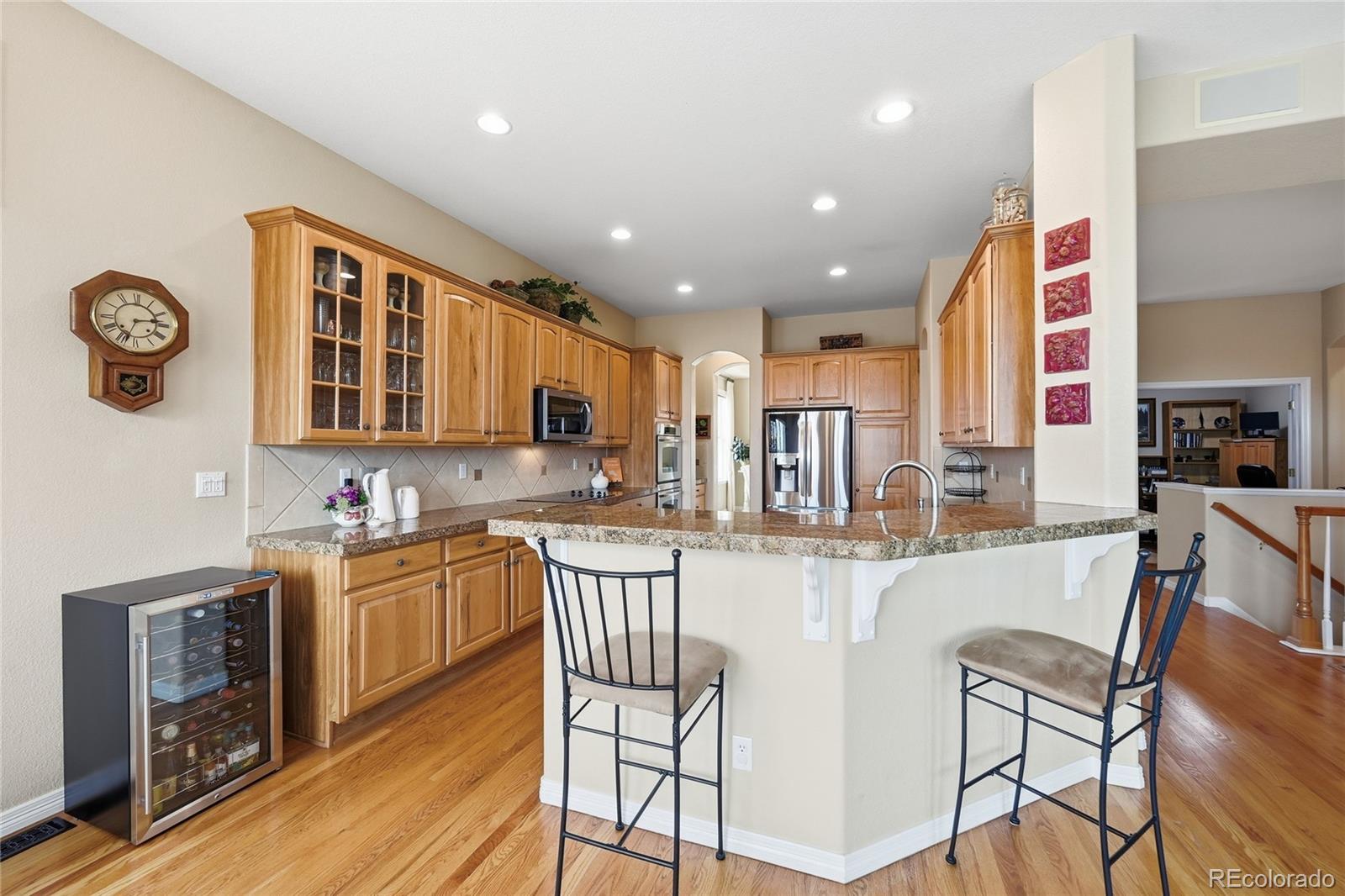 2626 Pemberly Avenue Highlands Ranch, CO 80126 - Photo 6 of 49 a kitchen with stainless steel appliances granite countertop a refrigerator and a stove top oven with wooden floor
