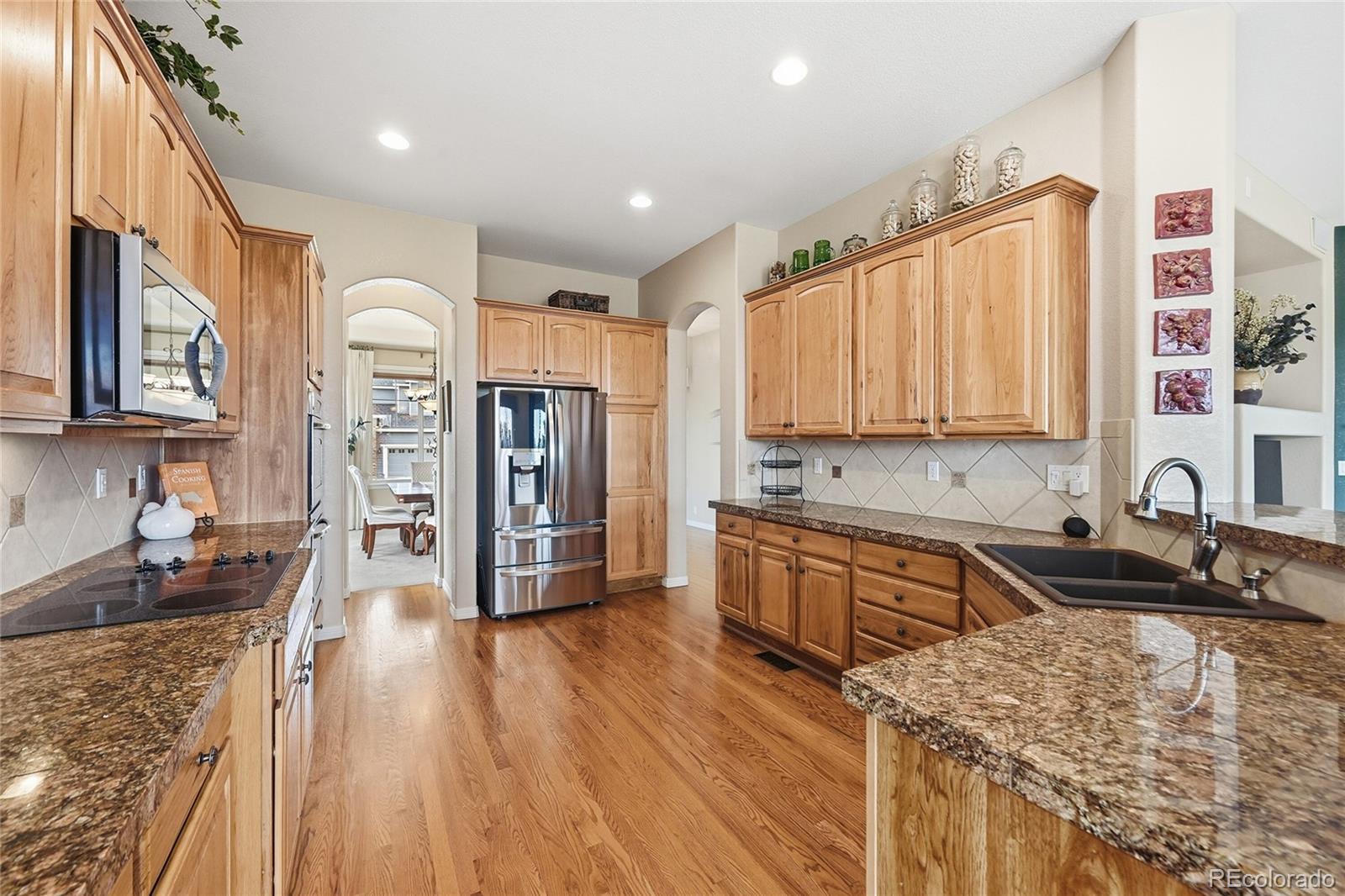 2626 Pemberly Avenue Highlands Ranch, CO 80126 - Photo 7 of 49 a kitchen with stainless steel appliances granite countertop a refrigerator a stove top oven and sink