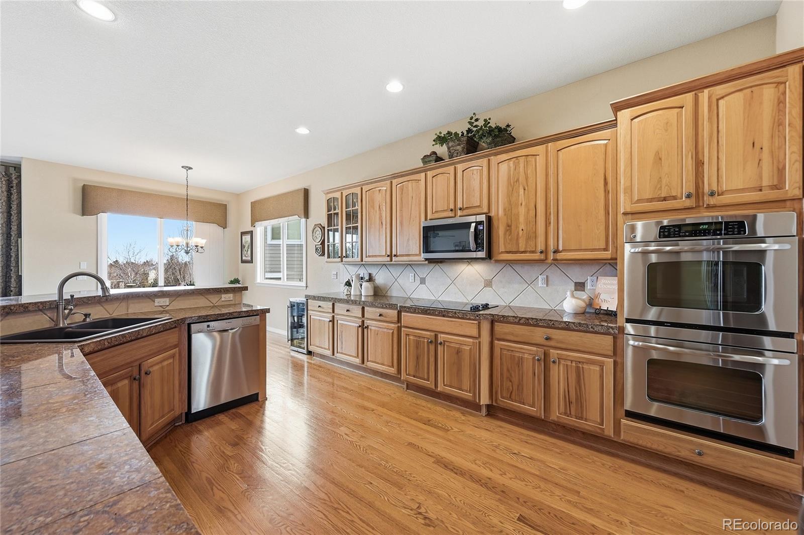 2626 Pemberly Avenue Highlands Ranch, CO 80126 - Photo 8 of 49 a kitchen with kitchen island granite countertop a sink cabinets and stainless steel appliances