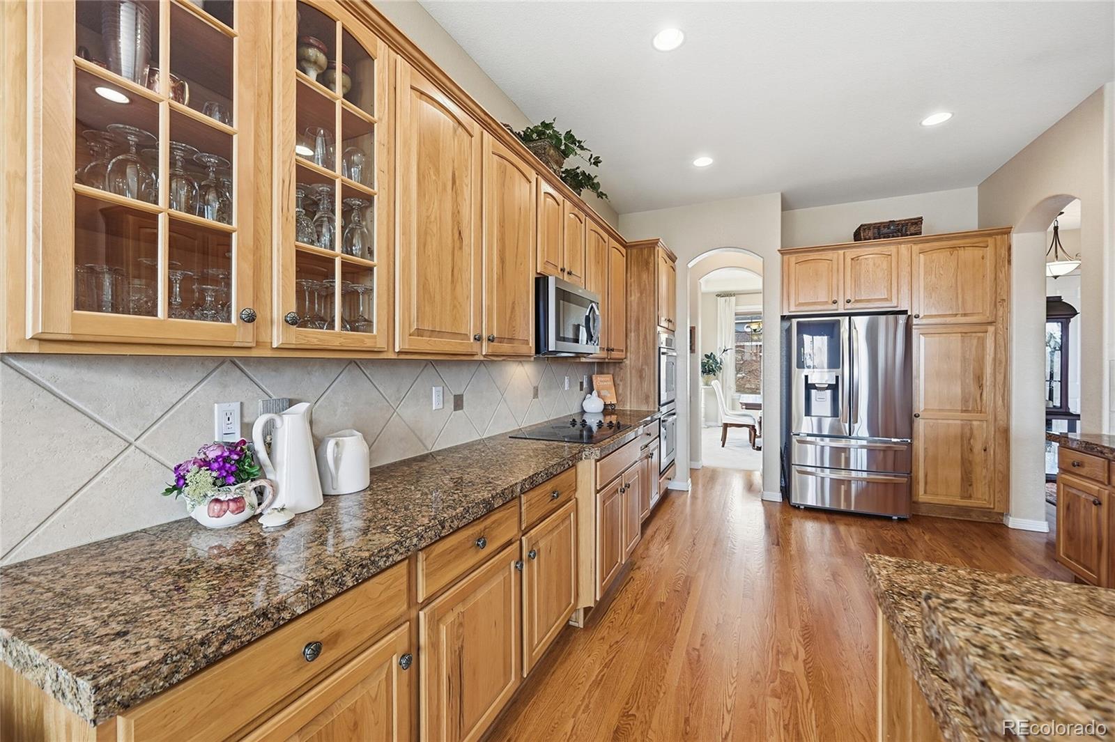 2626 Pemberly Avenue Highlands Ranch, CO 80126 - Photo 9 of 49 a kitchen with stainless steel appliances granite countertop lots of counter top space and wooden floor