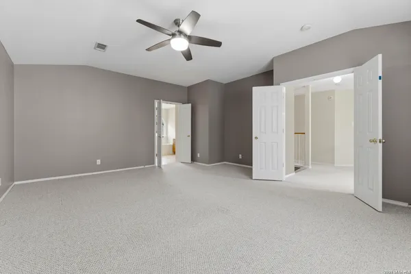 an empty room with chandelier fan and windows