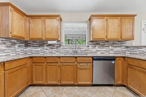 a kitchen with stainless steel appliances granite countertop white cabinets sink and window