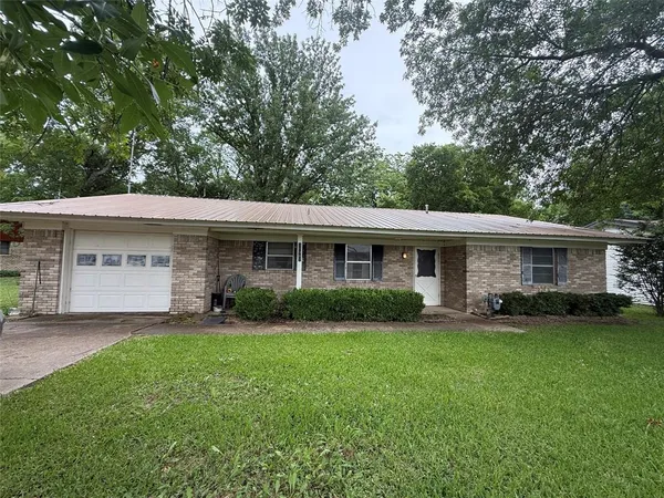 a front view of a house with a garden and trees