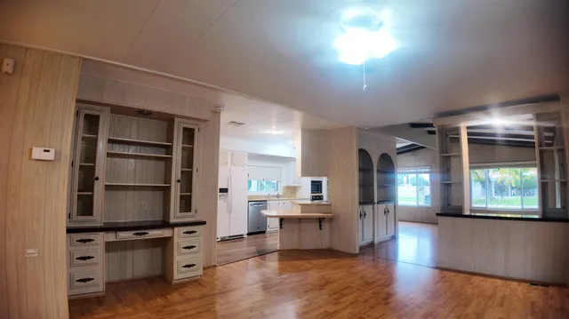 a kitchen with stainless steel appliances granite countertop a stove top oven a sink with wooden floors and cabinets