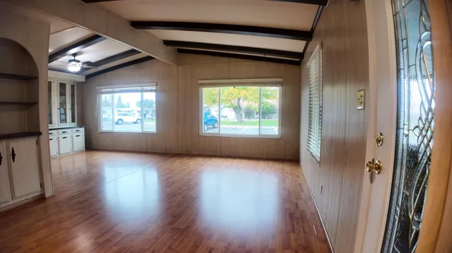 an empty room with wooden floor and windows