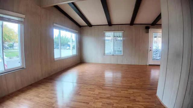 a view of an empty room with wooden floor and a window