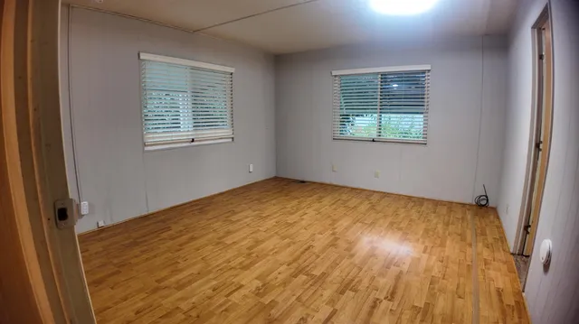 a view of empty room with wooden floor and fan