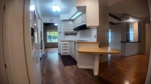 a kitchen with stainless steel appliances a refrigerator a sink dishwasher a stove and a dining table with wooden floor