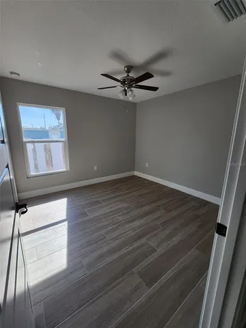 a view of empty room with wooden floor and fan