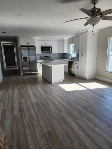 a view of kitchen with wooden floor electronic appliances and window