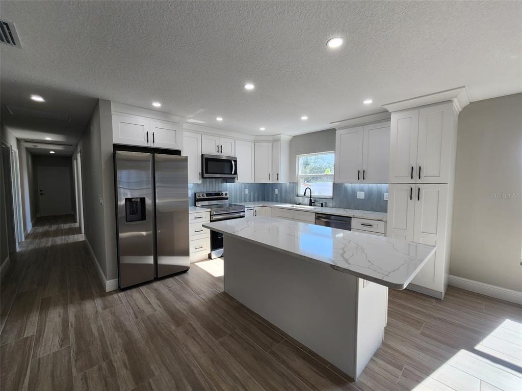 1013 13th Street East Bradenton, FL 34208 - Photo 10 of 14 a large kitchen with stainless steel appliances lots of counter space and a refrigerator