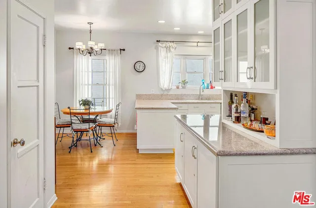 a very nice looking kitchen with granite countertop a stove a sink a dining table and chairs