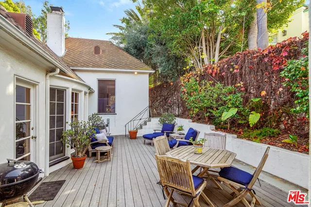 a view of a patio with table and chairs potted plants with wooden floor and fence