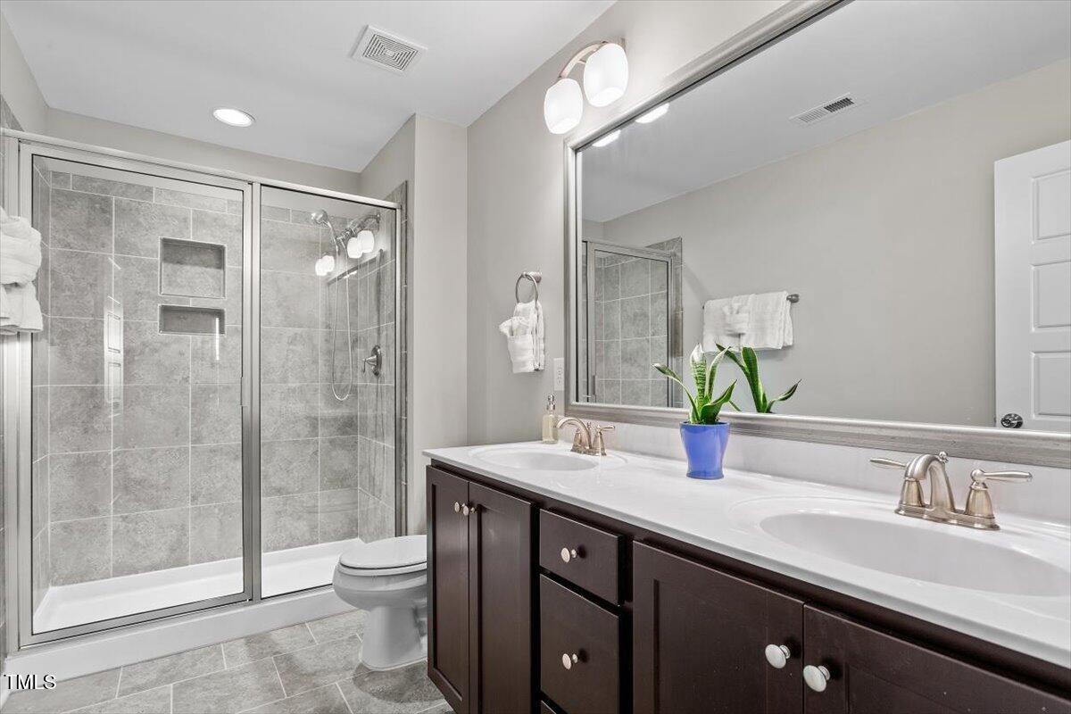 7822 Allscott Way Raleigh, NC 27612 - Photo 22 of 33 a bathroom with a double vanity sink toilet and shower