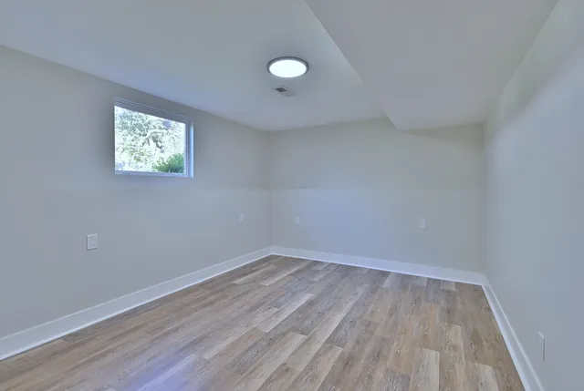 a view of empty room with wooden floor and fan