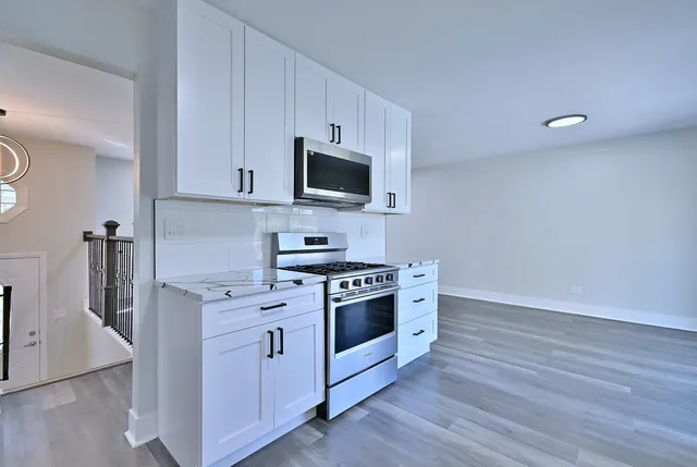 a kitchen with cabinets stainless steel appliances and wooden floor