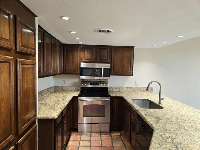 a kitchen with stainless steel appliances granite countertop a sink stove and refrigerator