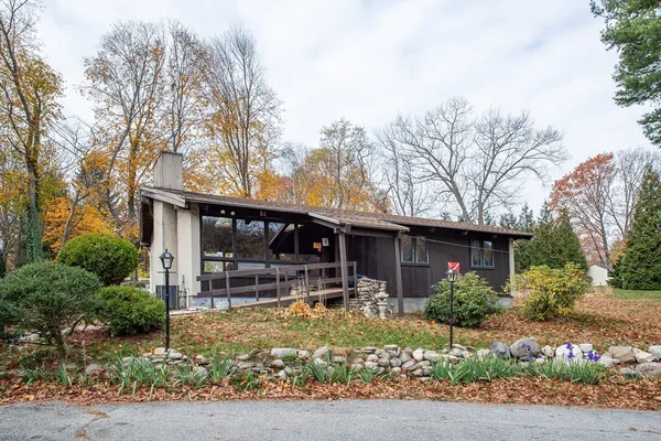 a front view of house with yard and trees in the background