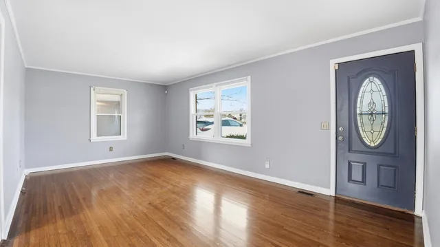 an empty room with wooden floor closet and windows