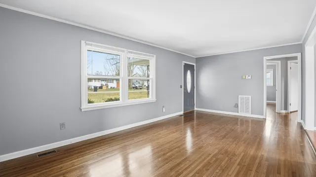 a view of an empty room with window and wooden floor