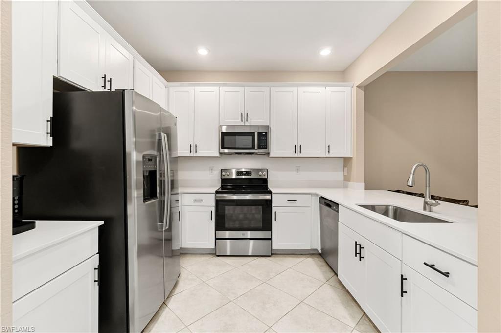2767 Blossom Way Naples, FL 34120 - Photo 4 of 38 a kitchen with white cabinets and stainless steel appliances