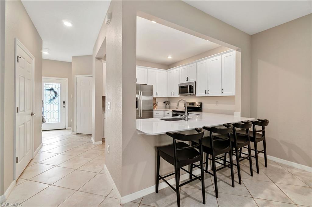 2767 Blossom Way Naples, FL 34120 - Photo 10 of 38 a kitchen with stainless steel appliances a table and chairs in it