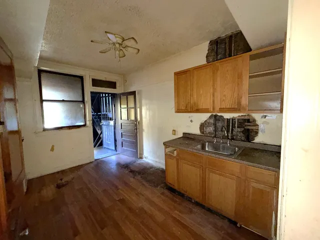 a kitchen with kitchen island granite countertop a sink cabinets and wooden floor