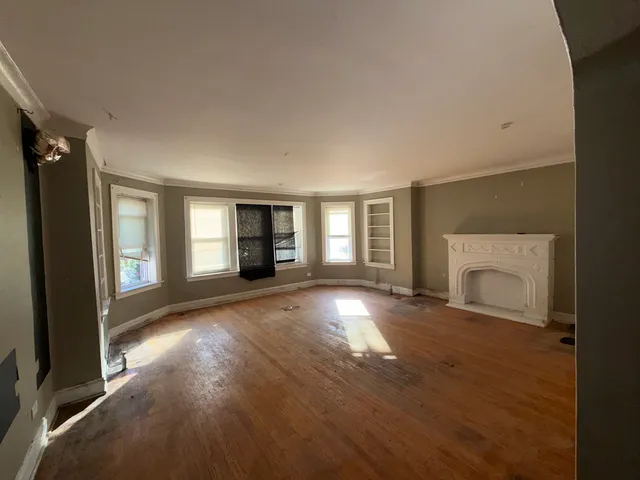 an empty room with windows and fireplace