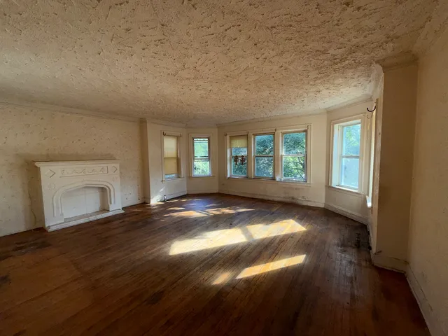 an empty room with wooden floor and fireplace