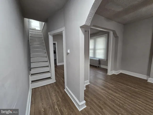 a view of a hallway with wooden floor and stairs