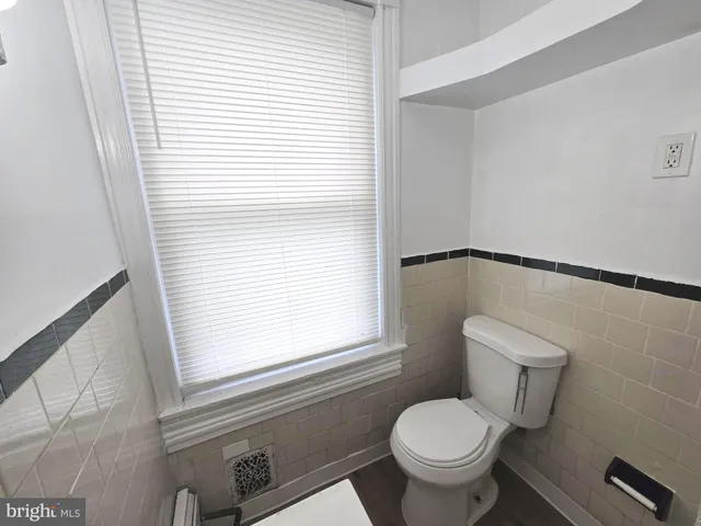 a white toilet sitting next to a window in a bathroom