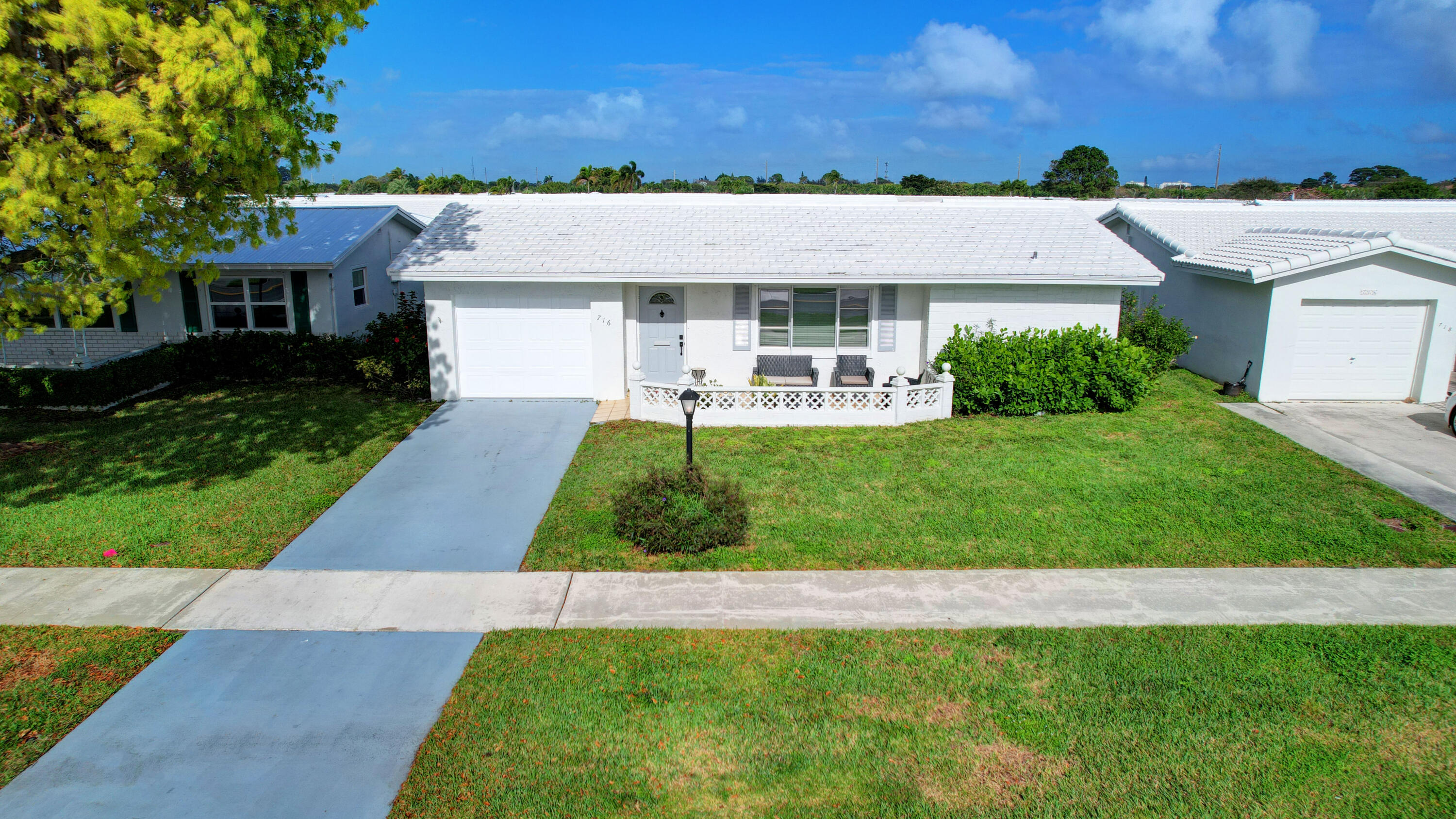 716 Southwest 18th Street Boynton Beach, FL 33426 - Photo 1 of 65 a view of a white house with a big yard and potted plants