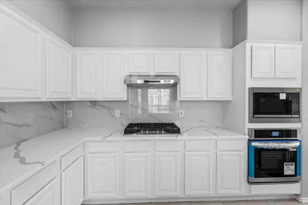 a kitchen with white cabinets and a stove top oven
