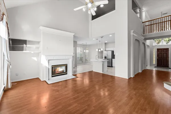 a view of a kitchen and an empty room with wooden floor and a kitchen