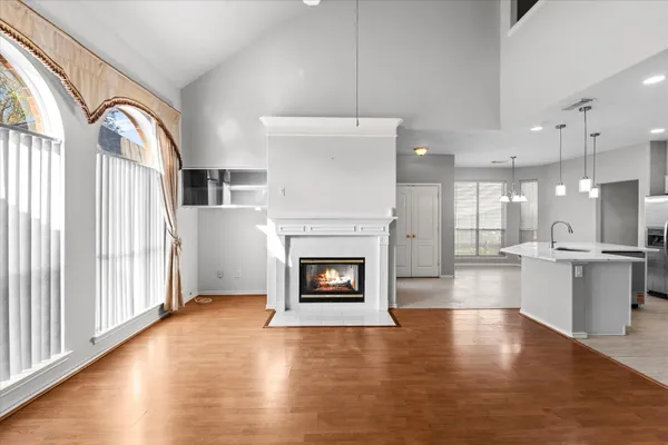 an empty room with wooden floor fireplace and windows