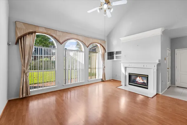 a view of an empty room with wooden floor fireplace and a window