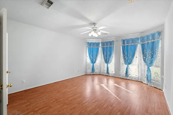 an empty room with wooden floor fan and a window