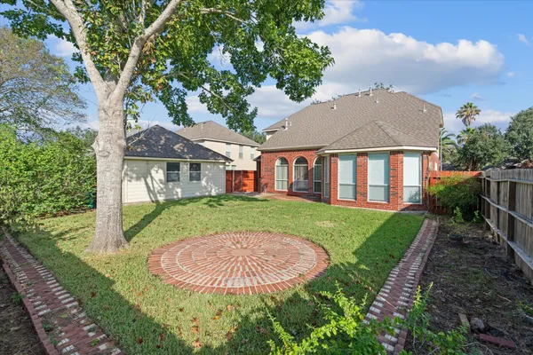 a view of a white house next to a yard with big trees