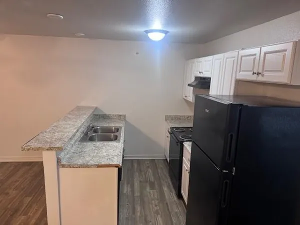 a kitchen with granite countertop a refrigerator a stove and wooden cabinets