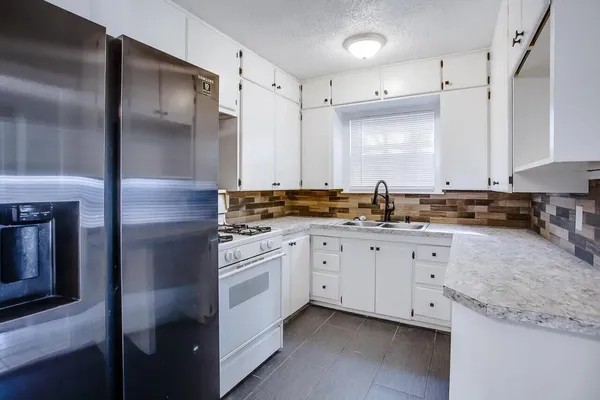 a kitchen with granite countertop white cabinets and stainless steel appliances