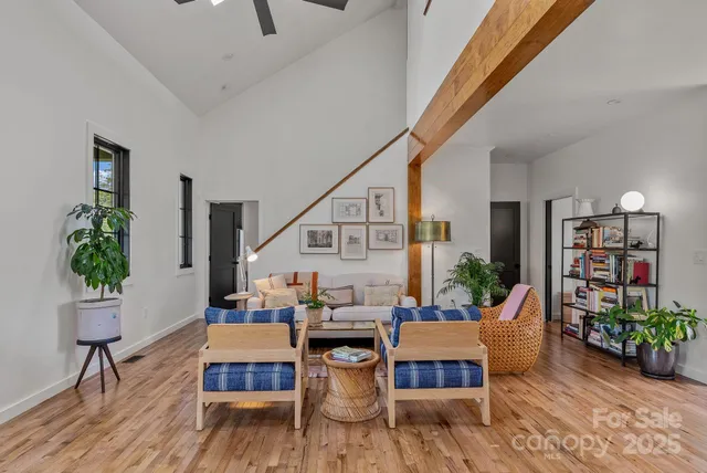 a living room with furniture potted plant kitchen view and a large window