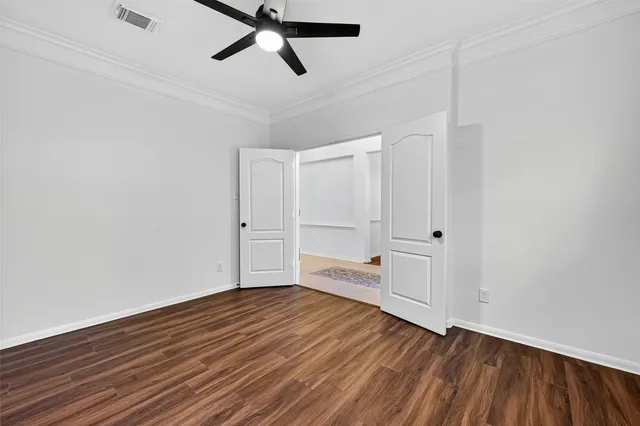 a view of empty room with wooden floor and ceiling fan