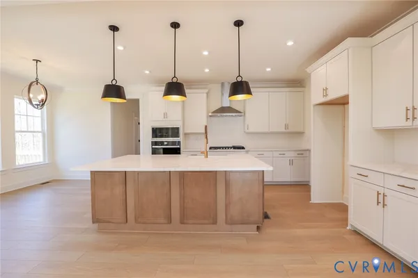 a kitchen with kitchen island a stove a counter space and a view of living room