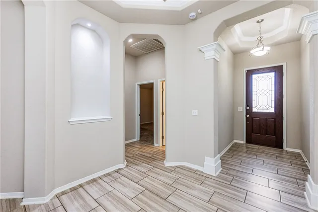 a view of a hallway with wooden floor and a bathroom