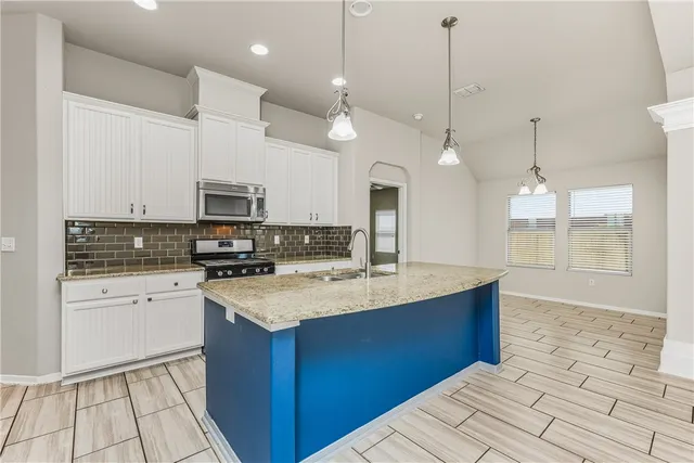 a large kitchen with stainless steel appliances kitchen island granite countertop a sink a stove and a refrigerator