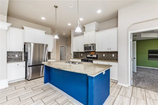 a kitchen with stainless steel appliances kitchen island granite countertop a refrigerator a sink and a stove