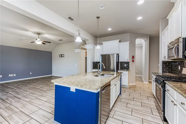 a large kitchen with stainless steel appliances kitchen island granite countertop a large counter top and stove in it